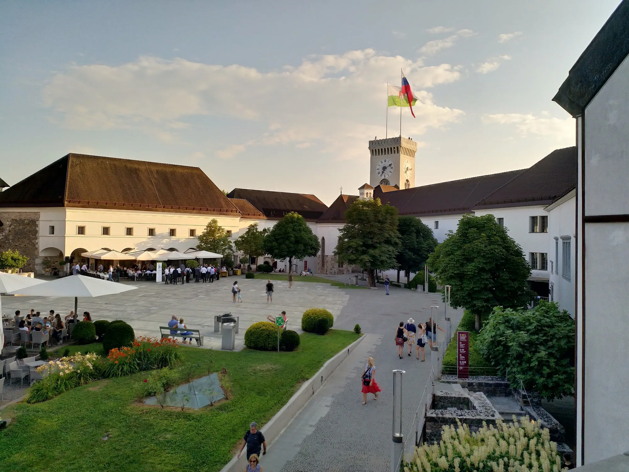 The inner courtyard of Ljubljana Castle with café tables and the viewing tower flying the Slovenian flag