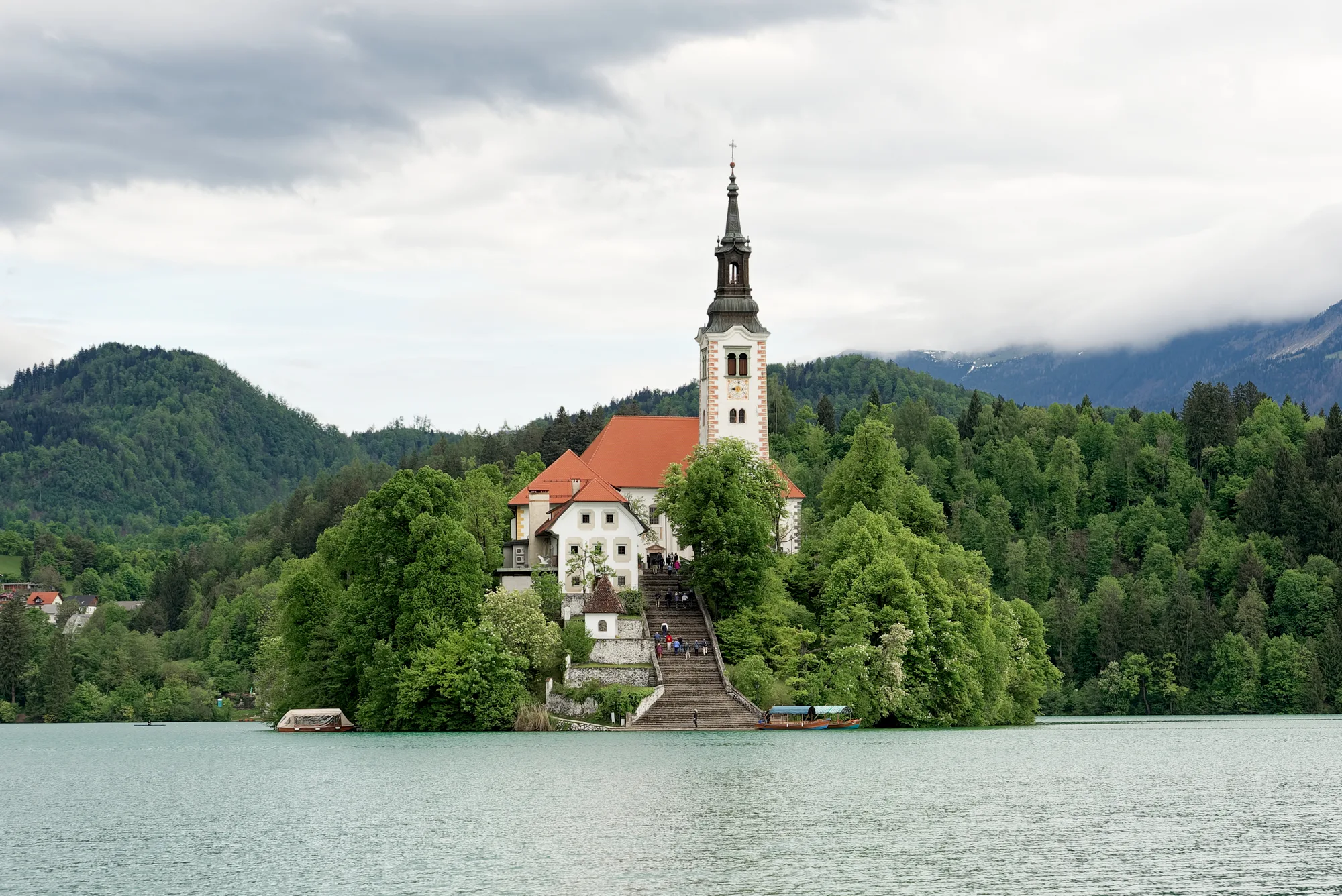 Bled Island and its pilgrimage church on Lake Bled, with a pletna boat and the Julian Alps behind