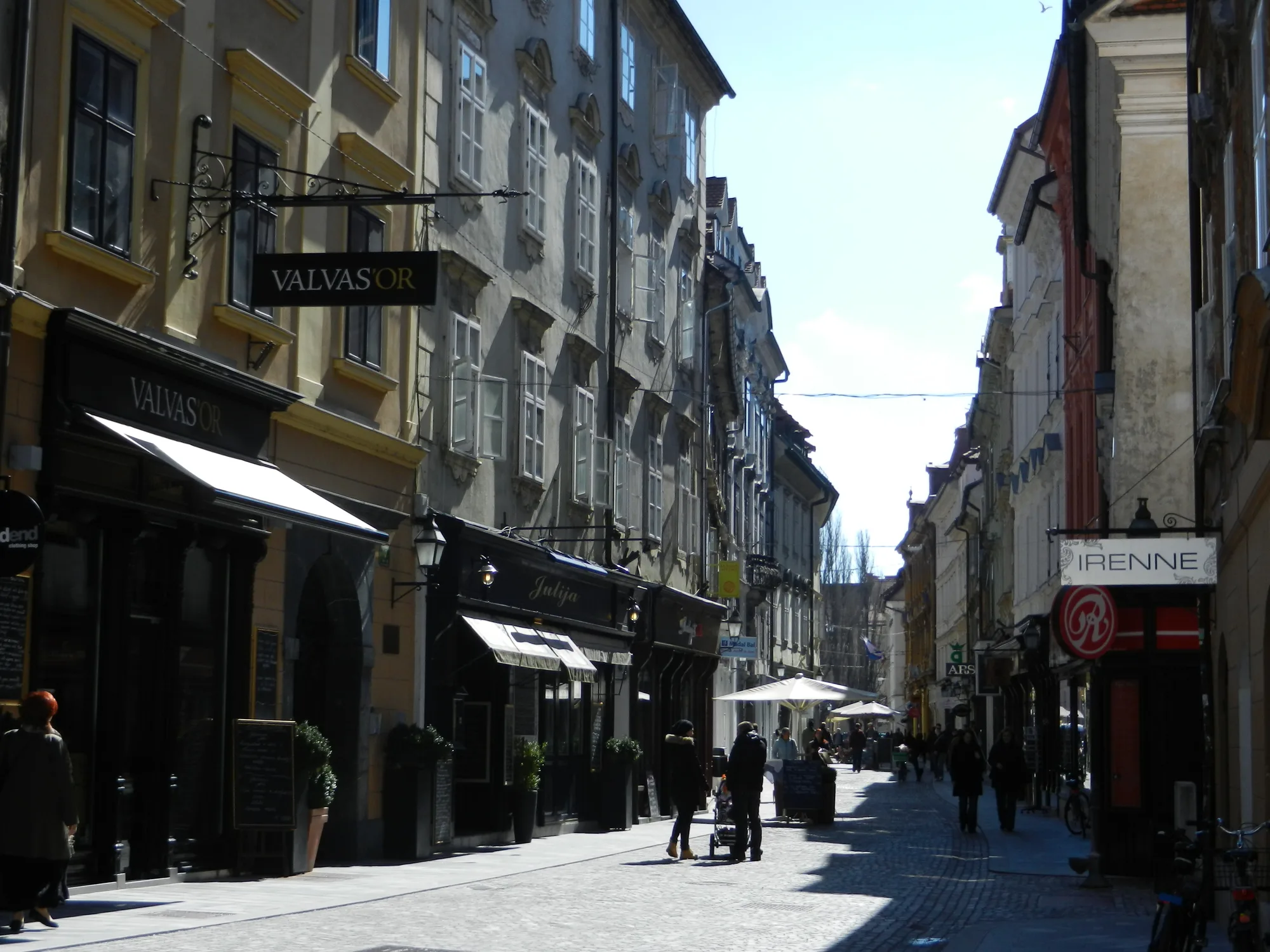 A cobbled old-town lane on Stari trg in Ljubljana, lined with pastel townhouses and café terraces
