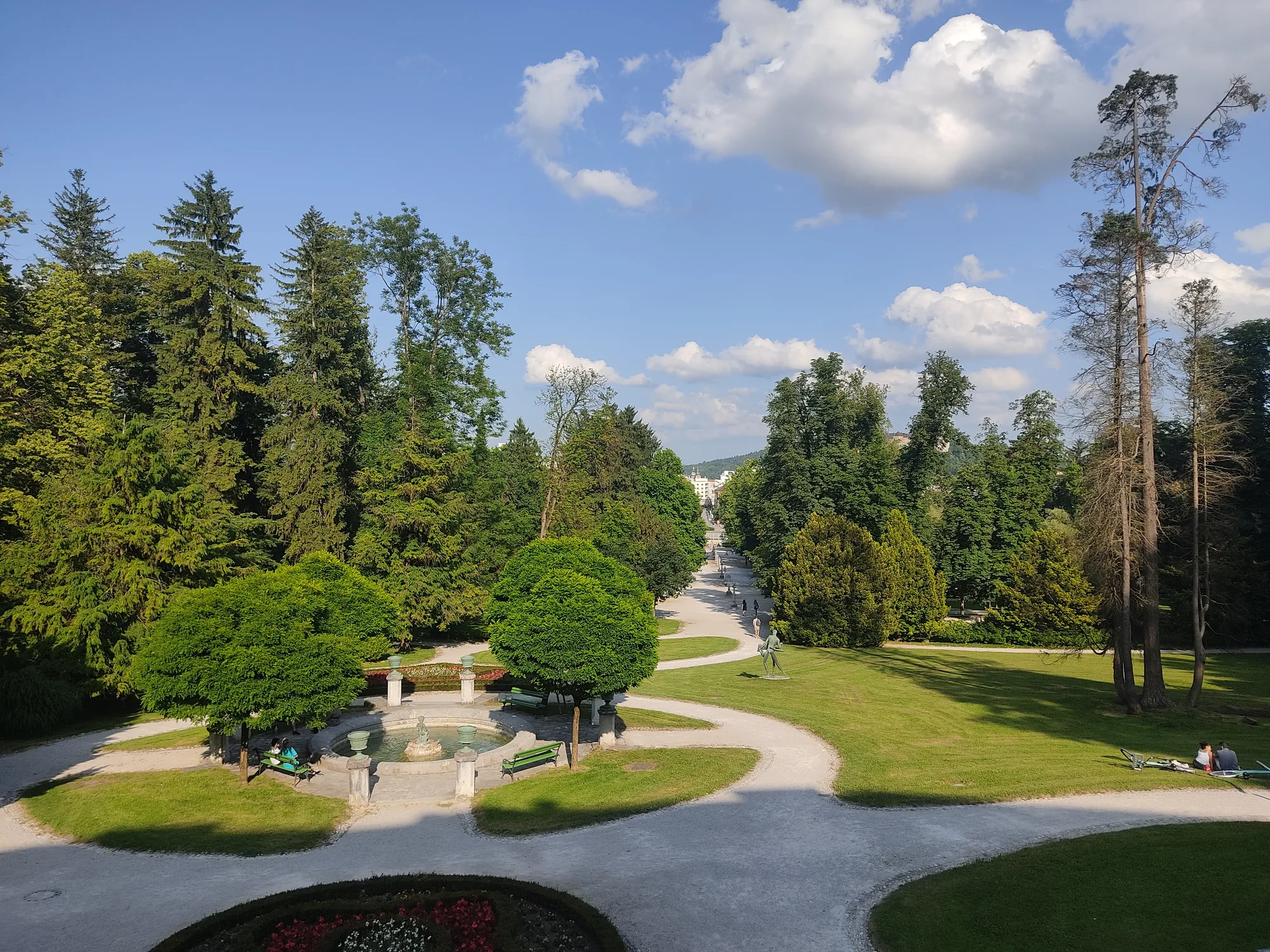 Green trees beside the water under a blue sky in Ljubljana's Tivoli Park